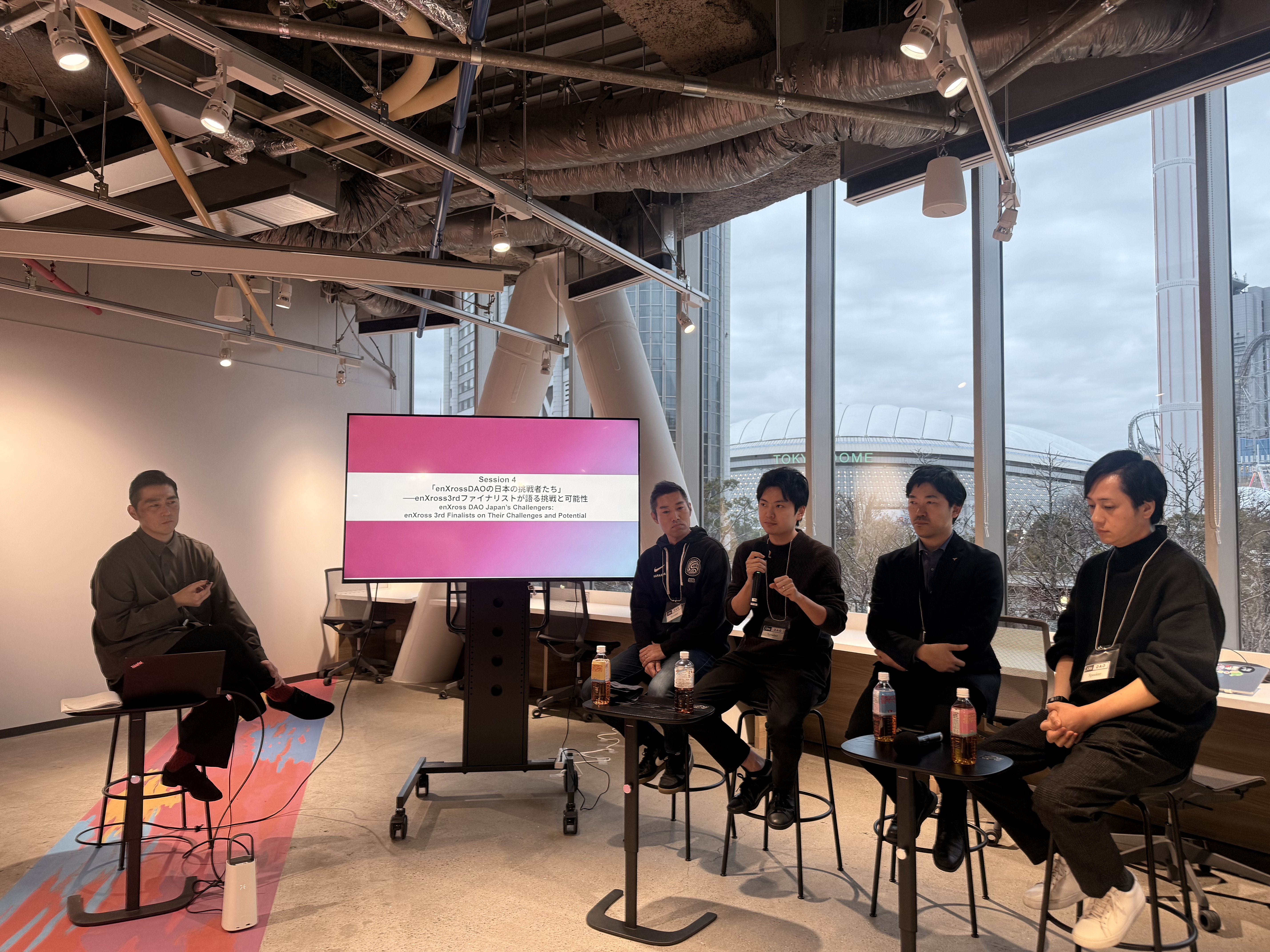 Panel discussion with Tokyo skyline visible through windows