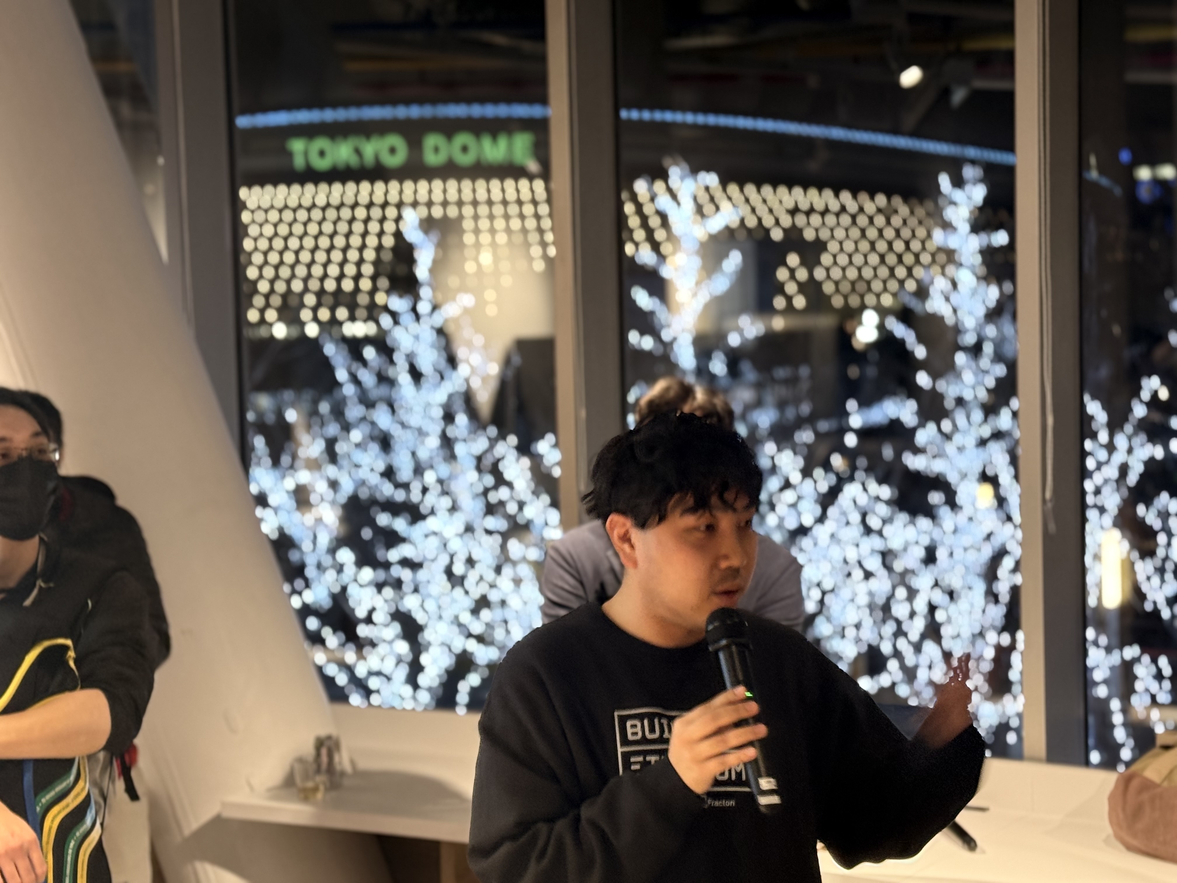 Speaker presenting with Tokyo Dome illuminated in the background