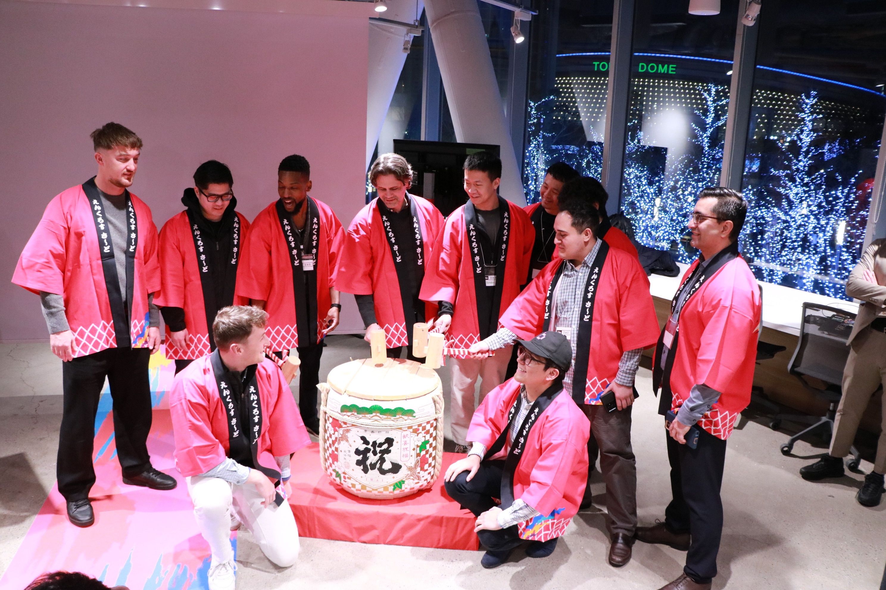 Team performing kagami biraki sake barrel ceremony in traditional happi coats